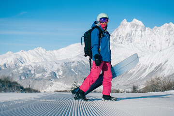 Female snowboarder walking on Snow trail from ratrak preparation, freshly groomed ski slope in high...