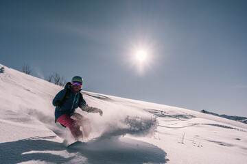 female snowboarder riding on slope of powdery snow in high mountains. Freeride at ski resort,...