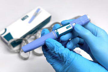 Hands in surgical gloves holding Ozempic Insulin injection pen for diabetics.