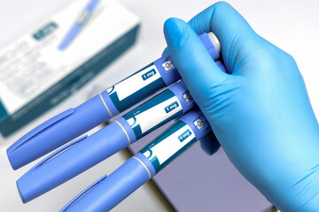Hands in surgical gloves holding Ozempic Insulin injection pen for diabetics.