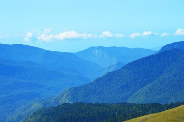 Blue mountains and green hills against a light blue sky. Beautiful tourist summer landscape