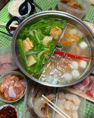 High angle view of family reunion dinner, hotpot or steamboat during Chinese New Year, where raw ingredients like meat, seafood and vegetables are cooked in a steel pot during the meal