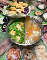 High angle view of family reunion dinner, hotpot or steamboat during Chinese New Year, where raw ingredients like meat, seafood and vegetables are cooked in a steel pot during the meal