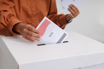 Close up of Asian hijab woman inserting and putting the voting paper into the ballot box. General...