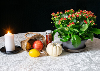 still life on white tablecloth, burning candle, bright flower and other objects