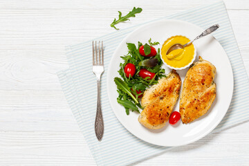 fried chicken breasts with green salad on plate