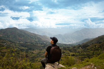 Una hombre turista con una mochila contemplando el asombroso paisaje de los Andes Peruanos con los...