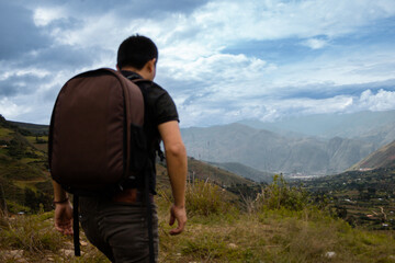 Una hombre turista caminando con una mochila contemplando el asombroso paisaje de los Andes...