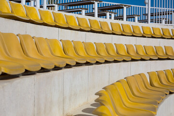 Round rows with yellow empty seats for street performances on a sunny day. No spectators at an...