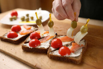 Olives and onions are added to the sandwich. Preparation of canapes with fish and vegetables