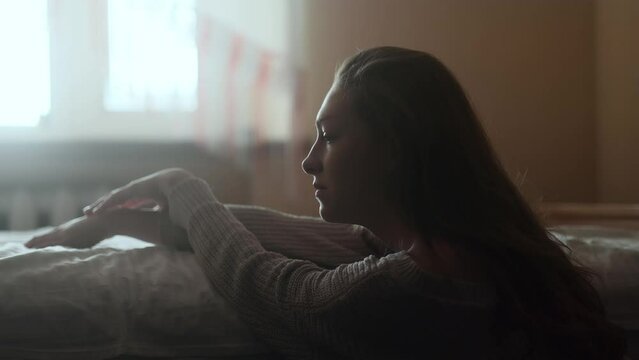 Portrait of sad young woman near the bed suffering from depression anxiety loneliness or mental health problem at home Thoughtful female upset feeling stress and pressure indoors