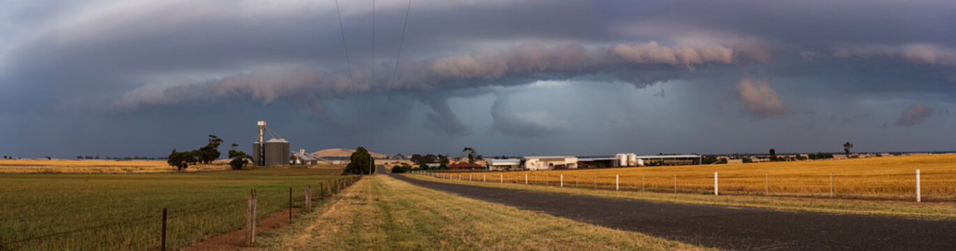 Panoramic view of a dramatic stormfront approaching over rural farmland and grand silos