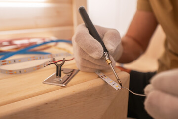 Electrician with Soldering Iron Attaching LED Stripe Cable - obrazy, fototapety, plakaty