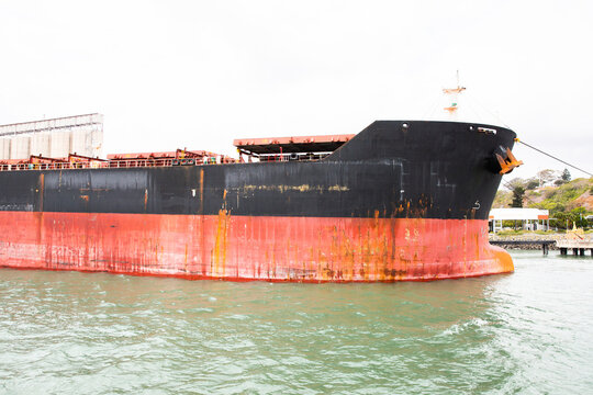 rusty red and black ship docked in Gladstone Harbour