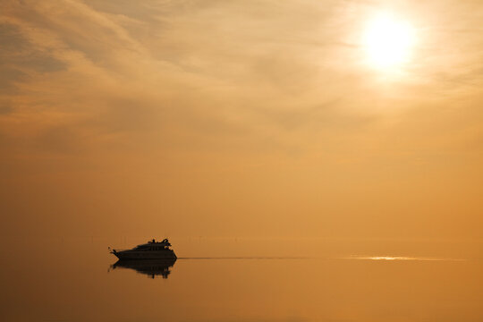 Recreatief varen met schip op de Oosterschelde in Zeeland, Nederland. De ondergaande zon geeft een oranje kleur over het water
