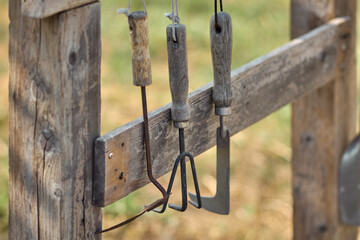 rusty gardening tools hanging on the wooden rack