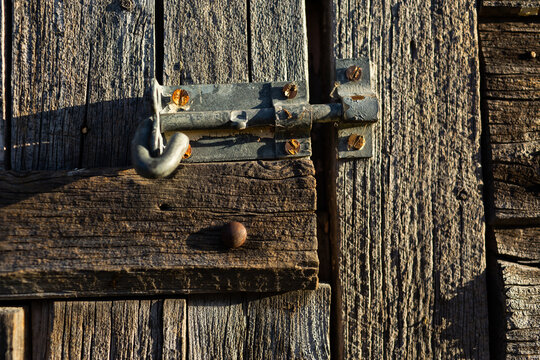 Old weather worn wooden stables with latch keeping door closed