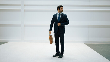 Professional business man standing with cool pose at white background. Manager holding bag while...