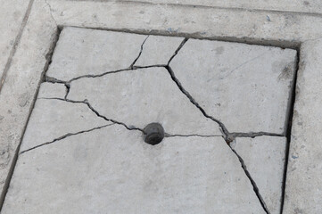 Cracked concrete drain cover on the cement road