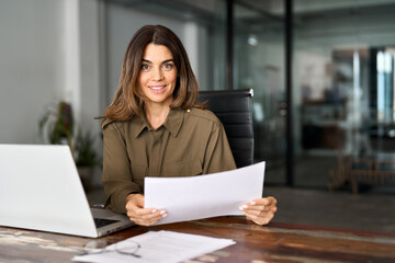 Smiling middle aged business woman working in office with laptop and document. Mature professional...