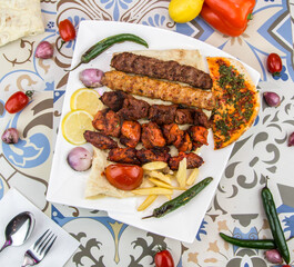 Assorted mix grills with tikka boti seekh kabab of chicken, beef, lamb, mutton, fries, pita bread bbq platter served in dish isolated on table top view of arabic food