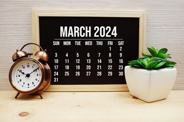 March 2024 monthly calendar and alarm clock on wooden background - obrazy, fototapety, plakaty