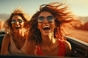 Fototapeten Two women enjoying a car ride in red convertible convert with wind in the hair, fun drive with friend © Irina Mikhailichenko