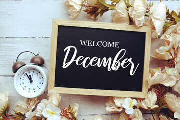 Welcome December text message with flower decoration on wooden background