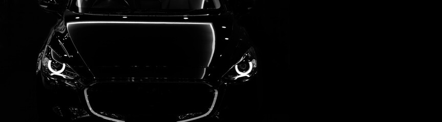Front view silhouette of black modern car with headlights on black background. copy space