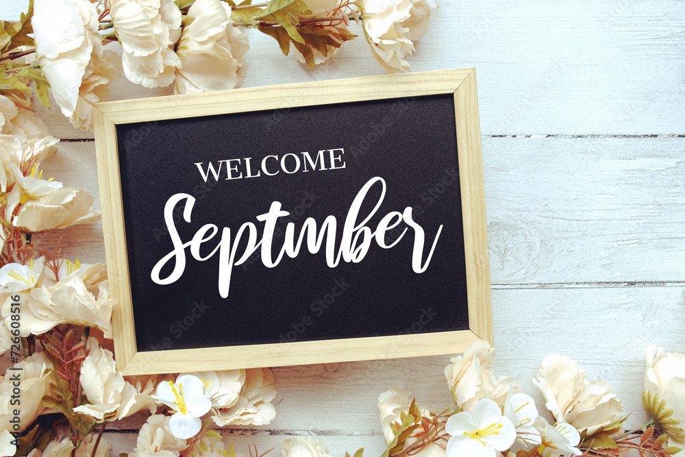 Wall mural Welcome September text message with flower decoration on wooden background