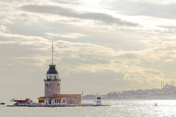 The Maiden's Tower basks in the soft glow of sunlight against a backdrop of Istanbul's skyline and sparkling Bosphorus waters, a serene moment in the city's vibrant life.