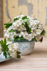 small bouquet of branch of a blooming hawthorn in vase on old shabby window sill,romantic mood and spring freshness