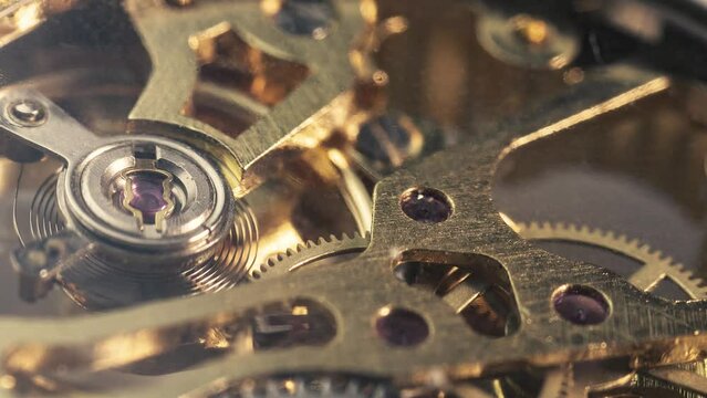 Metallic gears and cogs rotating inside mechanical clock.