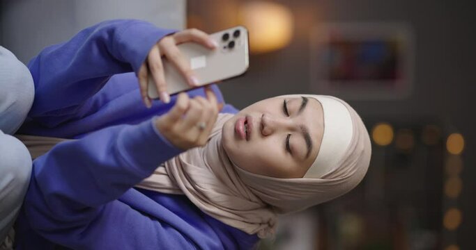 Woman using phone scrolling through. Female blogger scrolls through comments under videos photos rejoices laughs smiles receives positive feedback on content. Teen muslim blogger using social media