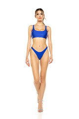 Naklejka premium Young beautiful brunette woman in blue bikini swimsuit walking on a white background.