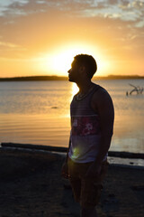 Silhouette of young man at sunset with lake in the background