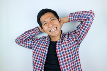 Smiling asian man with arm behind head relaxing peacefully in free time isolated on white background