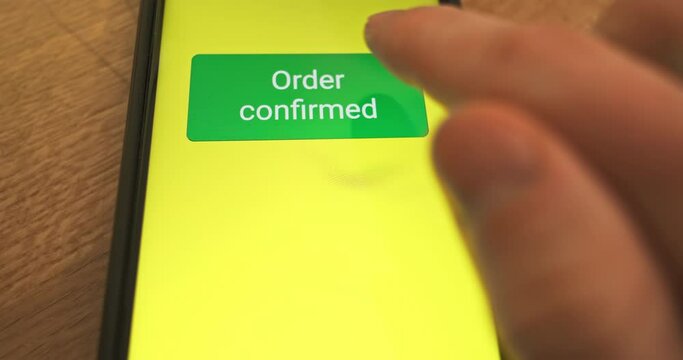 Pressing the Pay Now button on the smartphone screen. Order confirmed, response to purchase of goods, concept of online payment, online store. Close-up, front view.