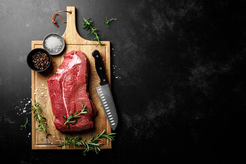 Beef meat entrecote on a cutting board, raw beef meat fillet on black background, top view - 726620901
