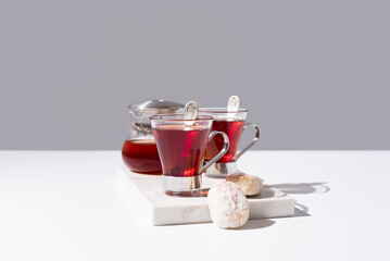 Té rojo con pasteles y dulces sobre mármol y fondo gris