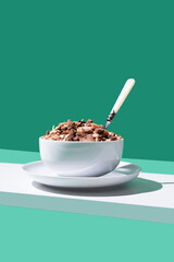 Cereal de granola muesli en un tazón blanco con cuchara sobre fondo verde 