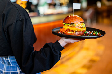 waitness holding plate with burger at cafe