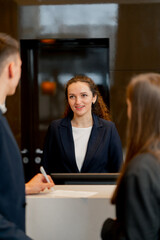 The receptionist at the counter meets guests with luggage in the hotel business travel hospitality