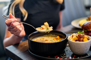 woman eating vegetable fish cream soup in bowl at cafe or restaurant