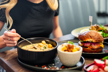 woman eating vegetable fish cream soup in bowl at cafe or restaurant