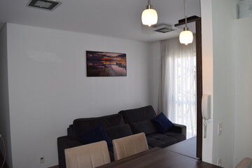 wide TV Room with a large dark-gray sofa couch. a open concept tablet conneting with kitchen, with a dark-wood rack and tablet, surrounded by 4 light caramel stuffed chairs.