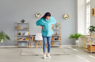 Pregnant woman weights herself on scales at home. Young woman with big belly standing on scales and...