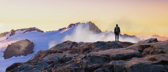 Adventurous Man Hiker on top of peak. Mountains in background. Adventure Composite 3d Rendering. Aerial Image of landscape from BC, Canada. Sunset