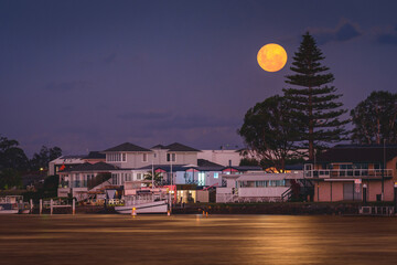 Full moon over the houses on the river bank.
