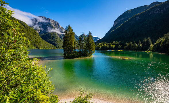 Alpine panorama of &ldquo;Lago del Predil&ldquo; or &ldquo;Raibler See&ldquo;, a green mountain lake near Tarvisio, Austria and Slovenia in the Julian alps with pine trees, island and reflection on a sunny summer day.